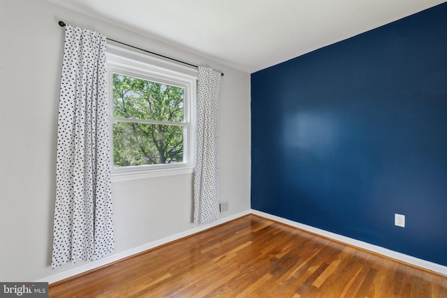 unfurnished room with baseboards and wood finished floors