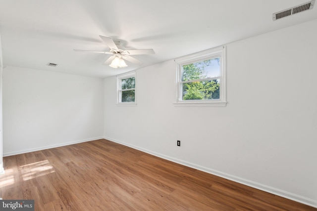 unfurnished room featuring baseboards, visible vents, and wood finished floors