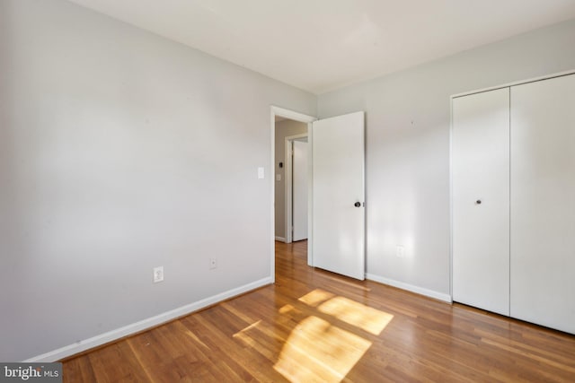 unfurnished bedroom with baseboards, wood finished floors, and a closet