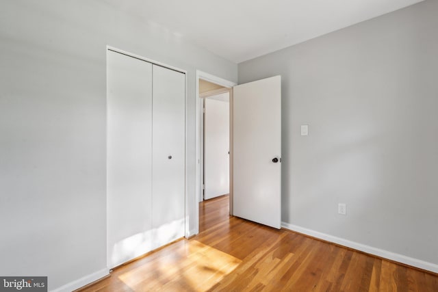 unfurnished bedroom with baseboards, light wood finished floors, and a closet
