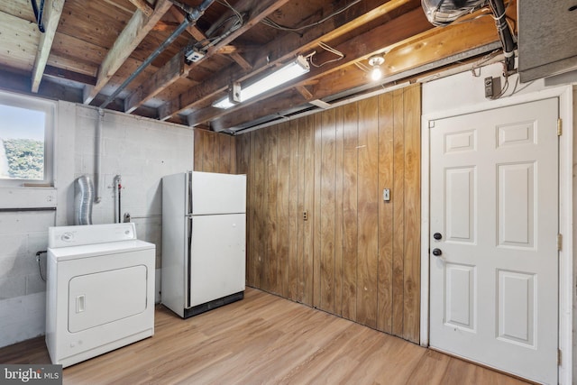 laundry room with laundry area, washer / clothes dryer, light wood-type flooring, concrete block wall, and wooden walls