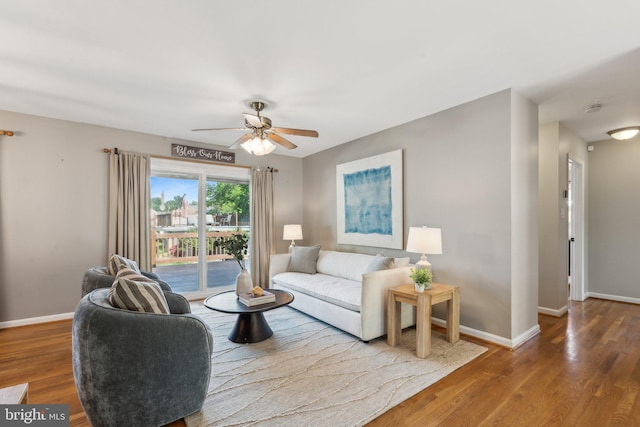 living area featuring baseboards, ceiling fan, and wood finished floors