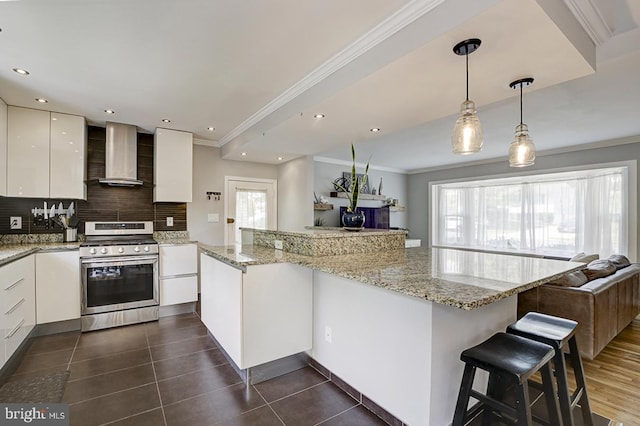 kitchen with stainless steel gas stove, wall chimney exhaust hood, ornamental molding, modern cabinets, and tasteful backsplash