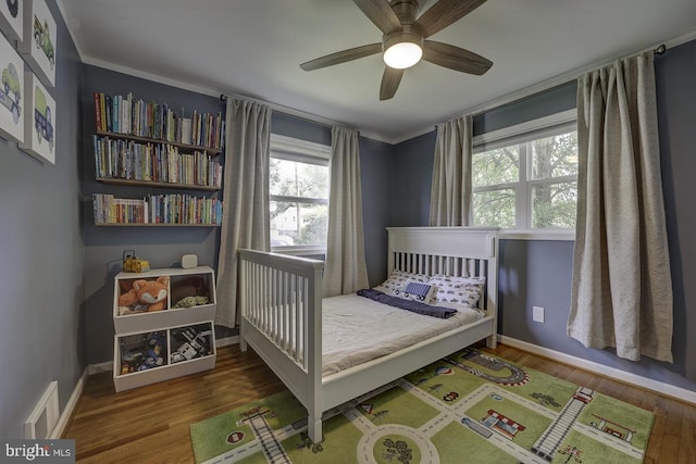 bedroom with multiple windows, wood finished floors, baseboards, and a ceiling fan