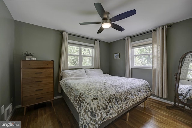 bedroom featuring multiple windows, dark wood-type flooring, and baseboards
