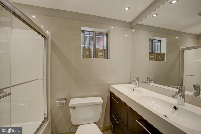 full bathroom featuring tile walls, an enclosed shower, toilet, recessed lighting, and double vanity