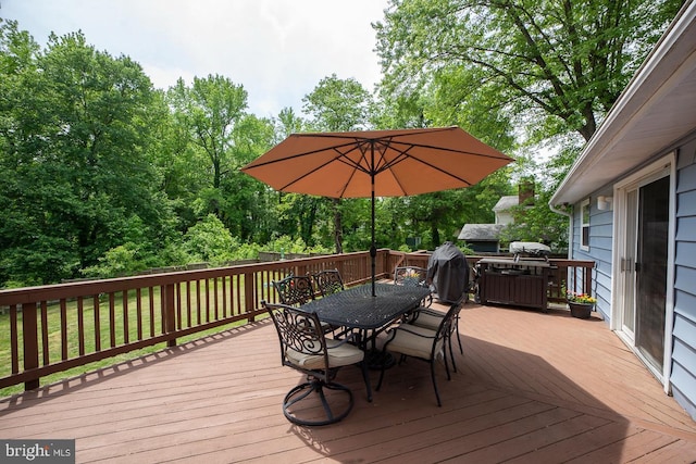 wooden deck featuring outdoor dining area and a lawn