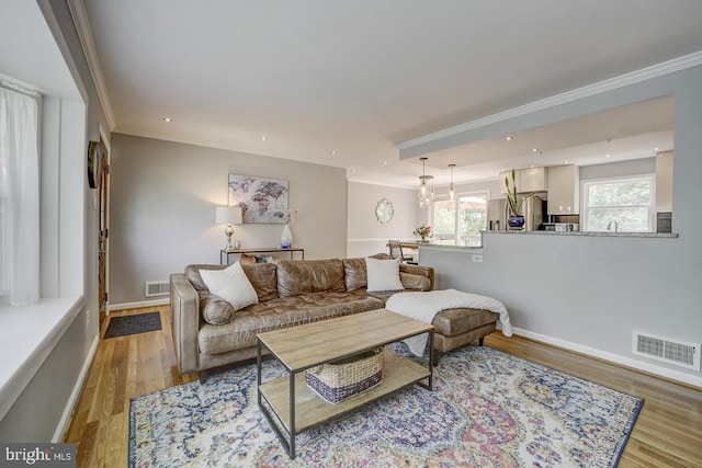 living room with crown molding, light wood finished floors, baseboards, and recessed lighting
