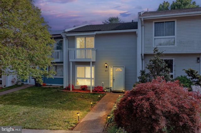 townhome / multi-family property featuring a lawn and a balcony