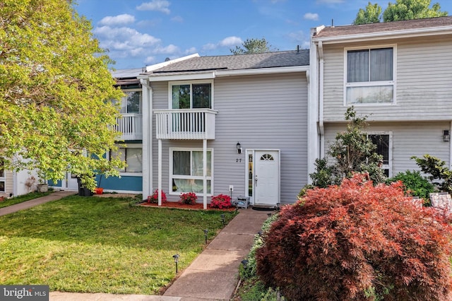 multi unit property featuring a front lawn, a balcony, and solar panels