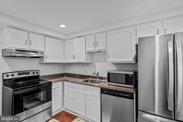 kitchen featuring recessed lighting, under cabinet range hood, white cabinets, a sink, and appliances with stainless steel finishes