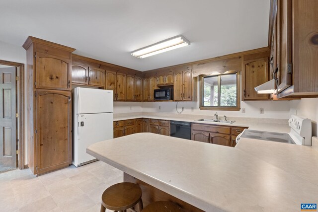 kitchen with a sink, light countertops, black appliances, a peninsula, and under cabinet range hood