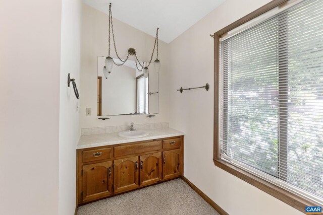 bathroom featuring a healthy amount of sunlight, vanity, and lofted ceiling