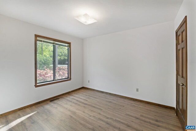 empty room featuring light wood-style floors, baseboards, and visible vents