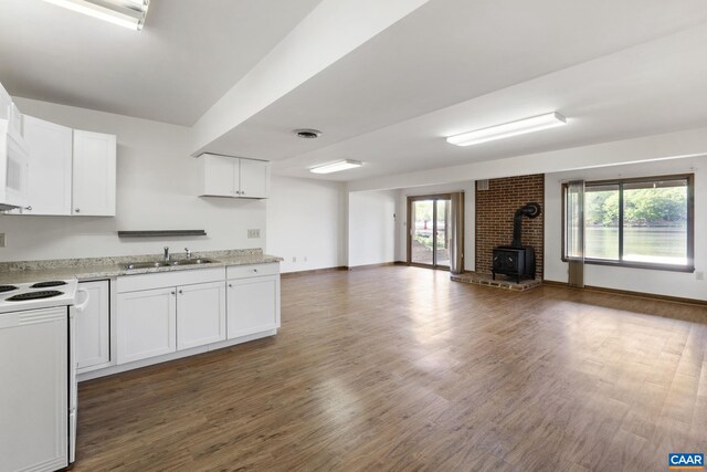 kitchen featuring a wood stove, open floor plan, white electric range, a sink, and dark wood finished floors