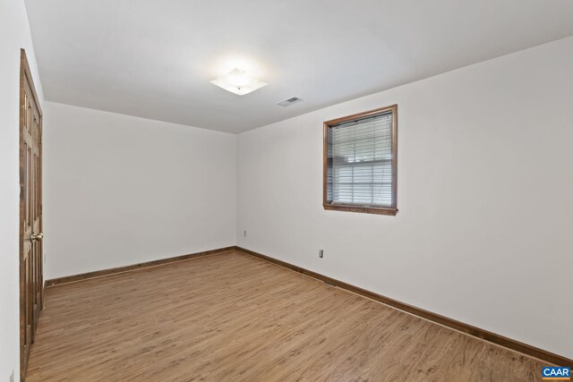 unfurnished room featuring baseboards, visible vents, and light wood-style floors