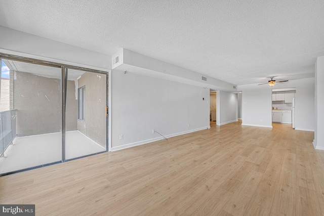 unfurnished living room with a textured ceiling, light wood-style flooring, a ceiling fan, baseboards, and visible vents