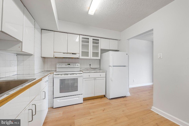 kitchen featuring white cabinets, white appliances, light countertops, a textured ceiling, and under cabinet range hood