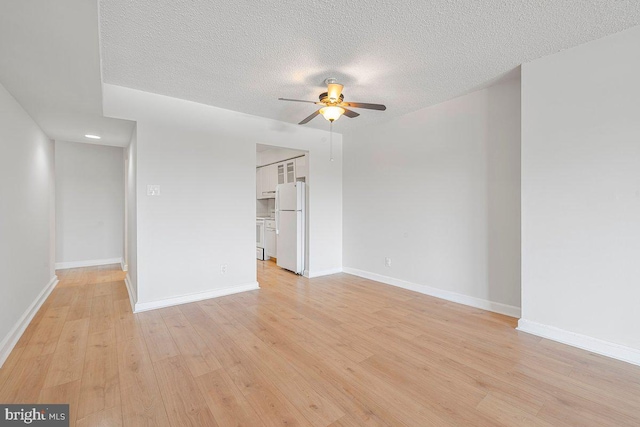 interior space with baseboards, a textured ceiling, light wood-style flooring, and ceiling fan