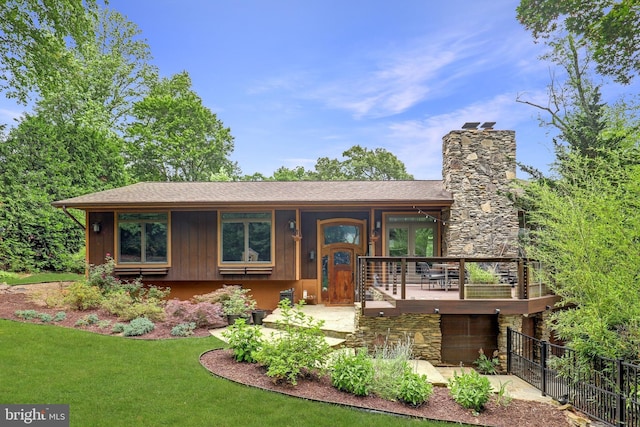 view of front of home with a chimney, stone siding, and roof with shingles