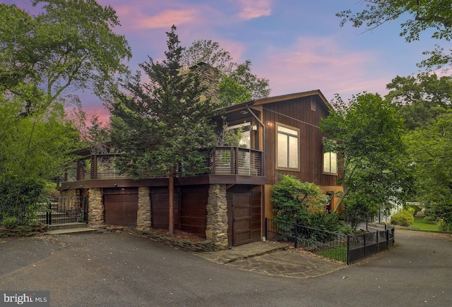 view of front of home with driveway, stone siding, and a balcony