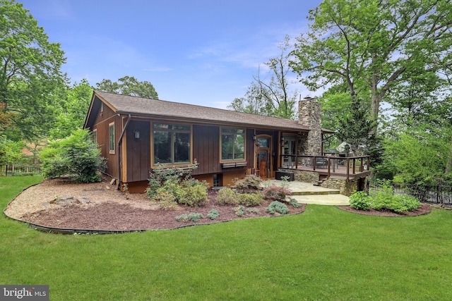 back of house with a chimney, a wooden deck, and a shingled roof