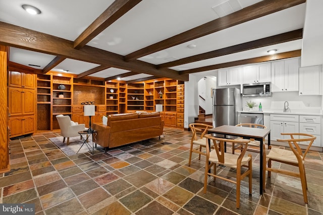 living area with arched walkways, stone tile floors, beam ceiling, built in shelves, and stairs