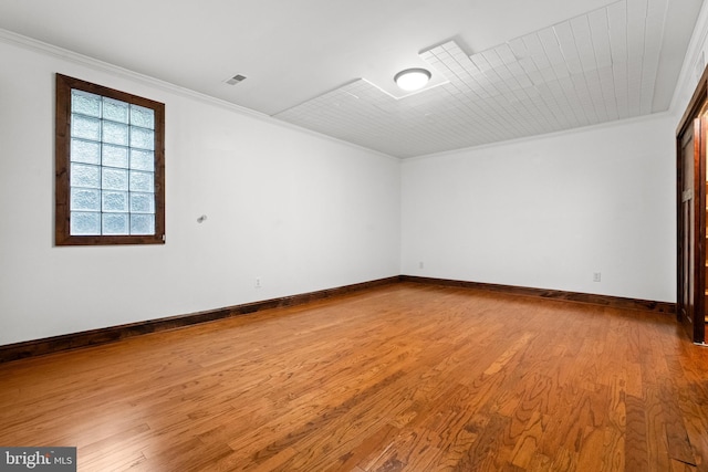 empty room with ornamental molding, wood finished floors, and baseboards