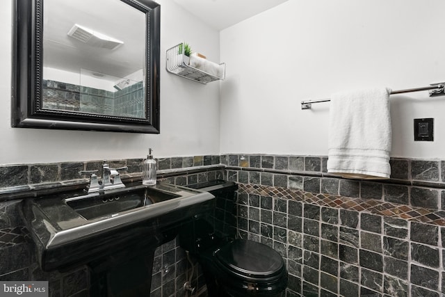 bathroom with tile walls, toilet, a wainscoted wall, and a shower