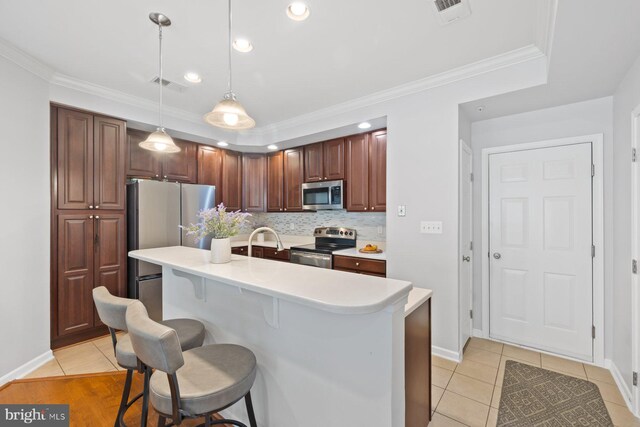 kitchen with appliances with stainless steel finishes, a breakfast bar, light countertops, backsplash, and visible vents