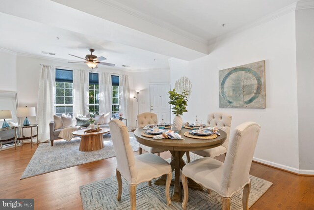 dining room featuring a ceiling fan, baseboards, wood finished floors, visible vents, and ornamental molding