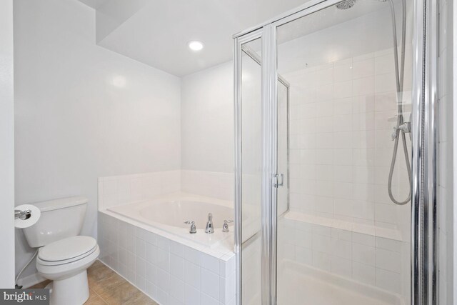 full bathroom featuring a garden tub, tile patterned floors, toilet, and a shower stall