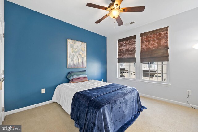 carpeted bedroom with visible vents, a ceiling fan, and baseboards