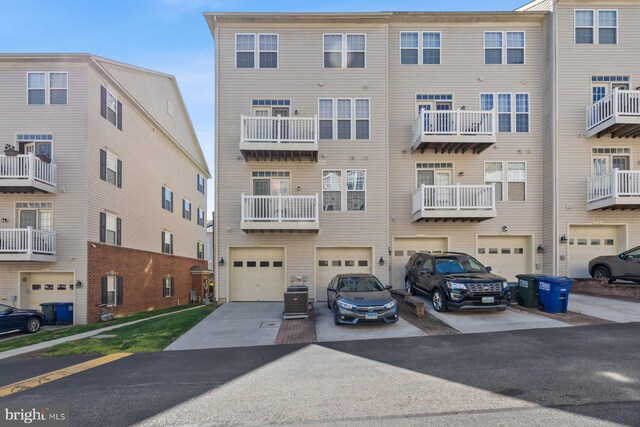 view of building exterior featuring a garage, central air condition unit, and driveway
