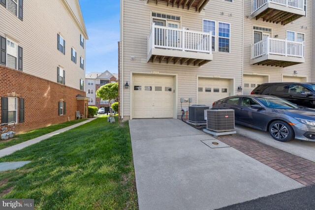 view of front of home featuring a garage, a front lawn, driveway, and cooling unit