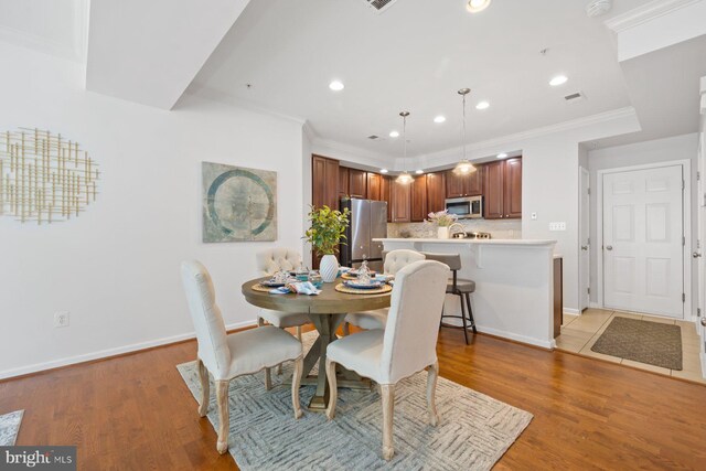 dining area with baseboards, ornamental molding, recessed lighting, and wood finished floors