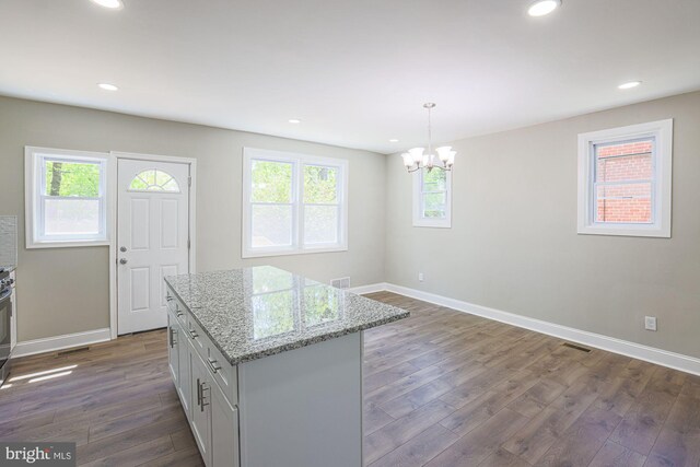 kitchen with baseboards, a chandelier, dark wood-style floors, and light stone countertops