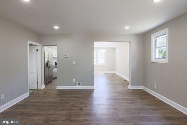 unfurnished room featuring visible vents, an inviting chandelier, baseboards, dark wood-style floors, and recessed lighting