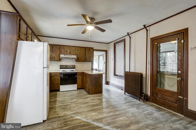 kitchen with freestanding refrigerator, radiator, range with electric stovetop, light countertops, and under cabinet range hood
