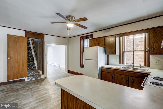 kitchen featuring ceiling fan, a sink, light countertops, freestanding refrigerator, and a baseboard heating unit