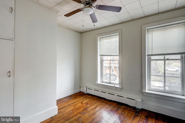 empty room featuring a baseboard radiator, a wealth of natural light, and hardwood / wood-style floors