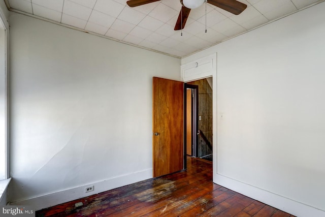 unfurnished room with baseboards, ceiling fan, and dark wood-type flooring
