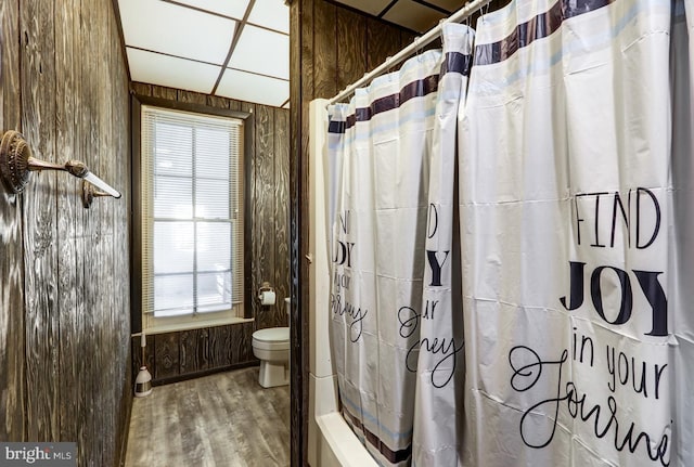 full bath with a shower with shower curtain, toilet, a healthy amount of sunlight, and wood finished floors