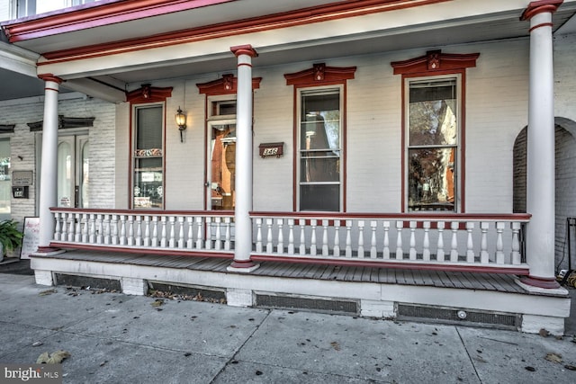 entrance to property with a porch and brick siding