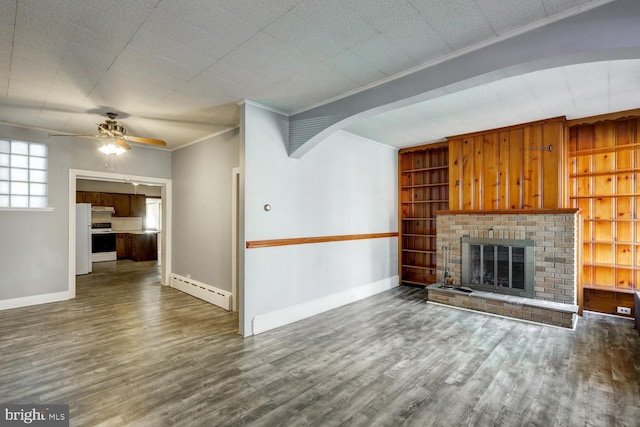 unfurnished living room with crown molding, a ceiling fan, baseboard heating, and wood finished floors