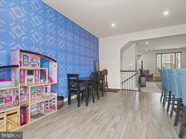 playroom with wallpapered walls, wood finished floors, an accent wall, baseboards, and recessed lighting