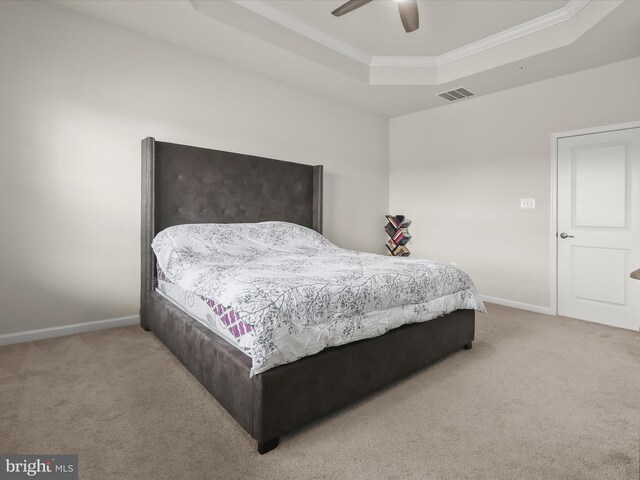 bedroom with a tray ceiling, carpet floors, ornamental molding, baseboards, and a ceiling fan