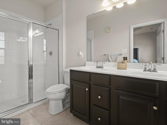 full bathroom featuring tile patterned flooring, a stall shower, toilet, and double vanity