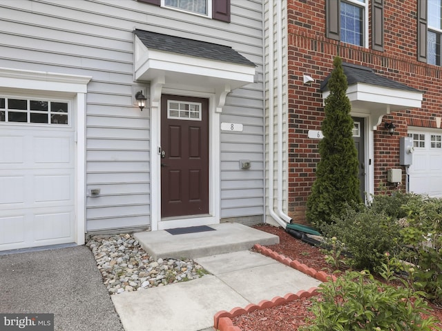 property entrance featuring a garage and brick siding