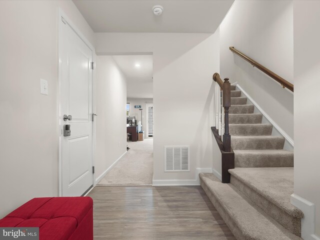 foyer with stairway, wood finished floors, and baseboards